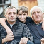 As boy with his father and grandfather hugging.